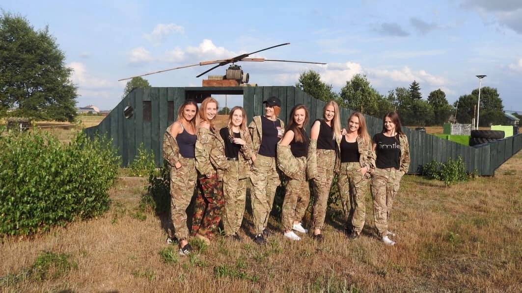 Grupa dziewczyn w mundurach polowych przed makietą helikoptera