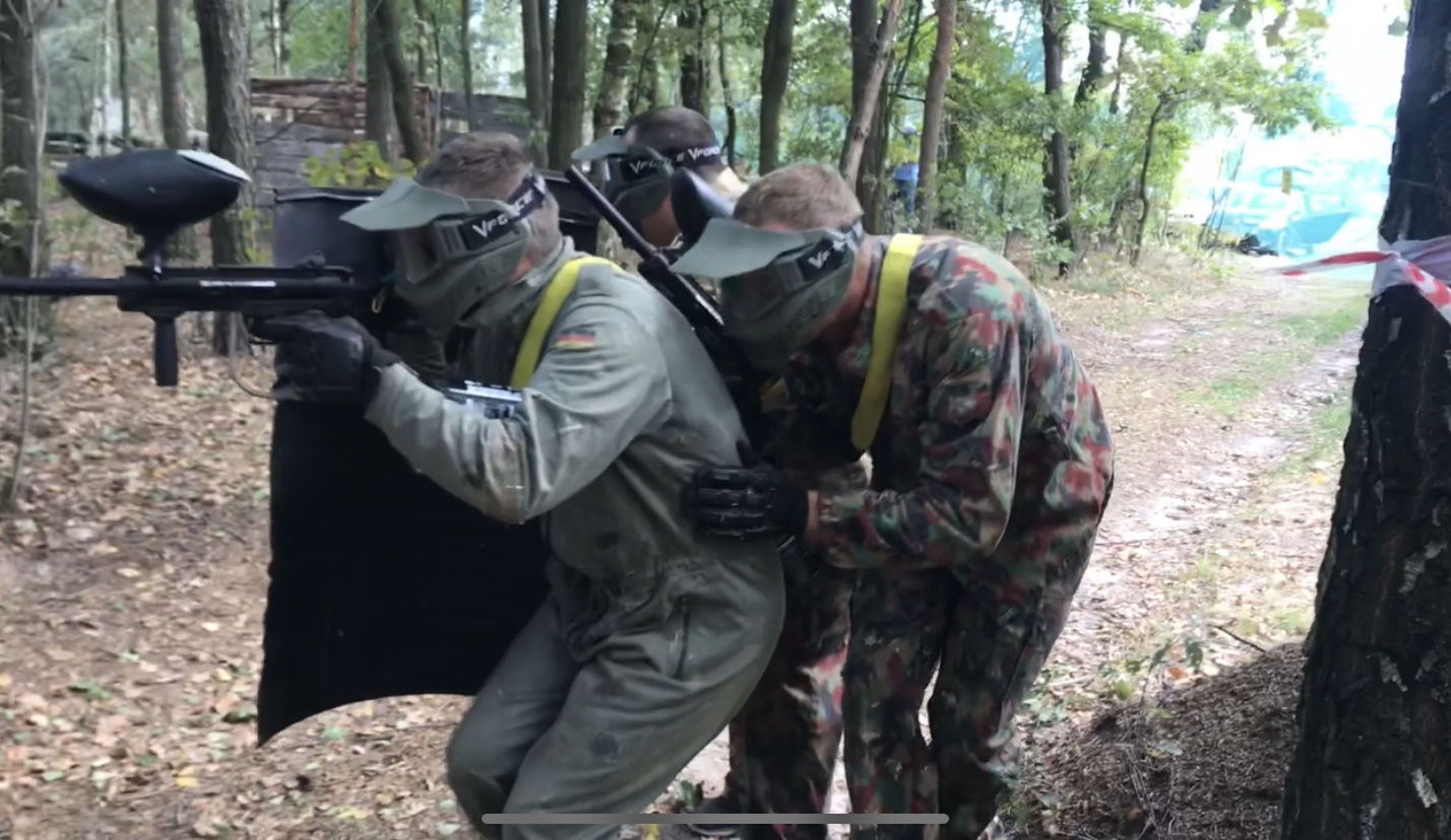 Drużyna paintballowa w akcji za osłoną w lesie