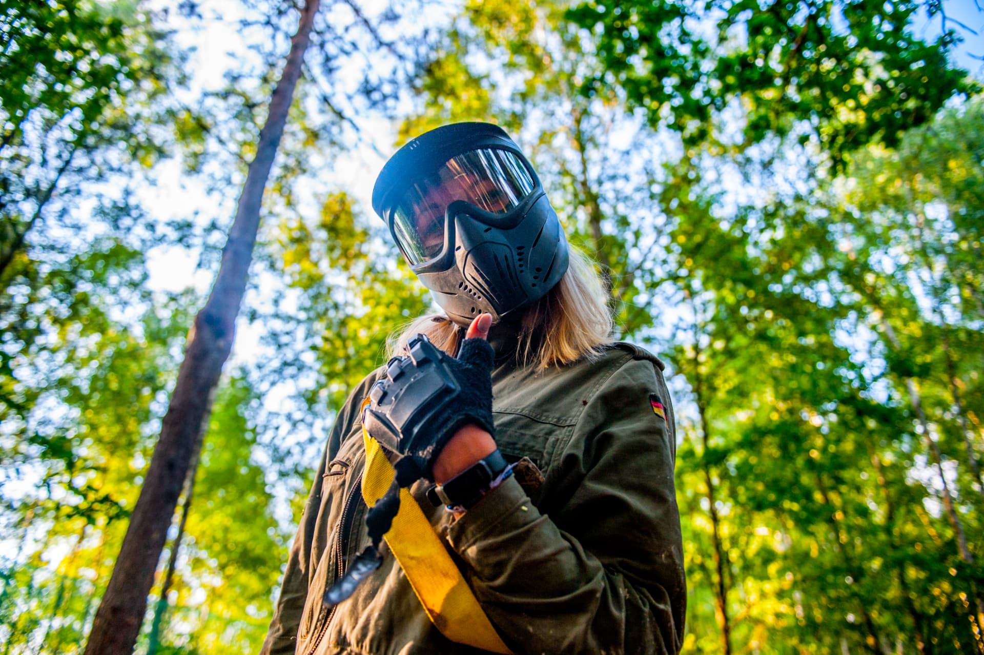 Gracz w masce paintballowej z żółtą opaską zwycięzcy w lesie