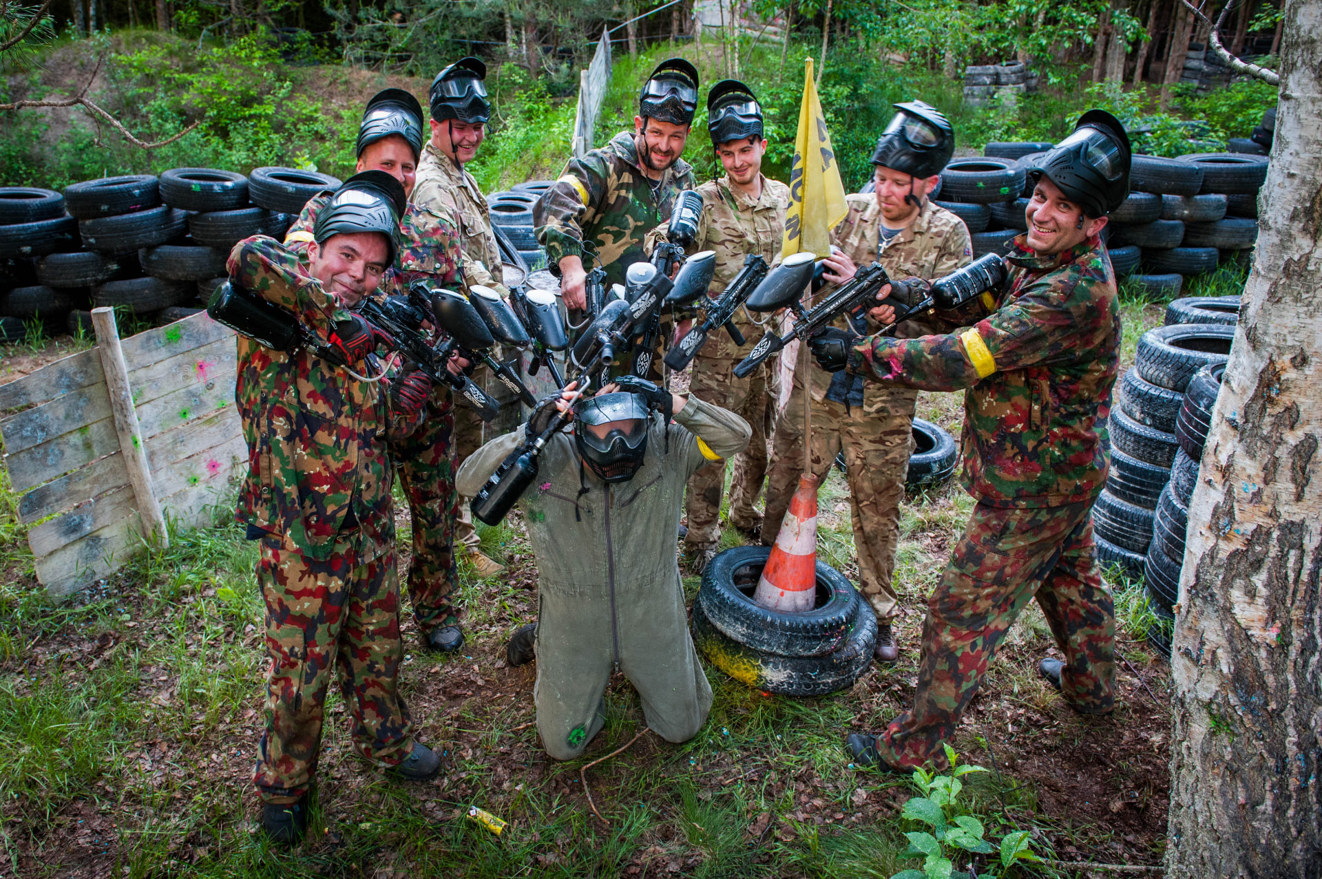 Drużyna paintballowa pozująca z markerami przy barykadzie z opon