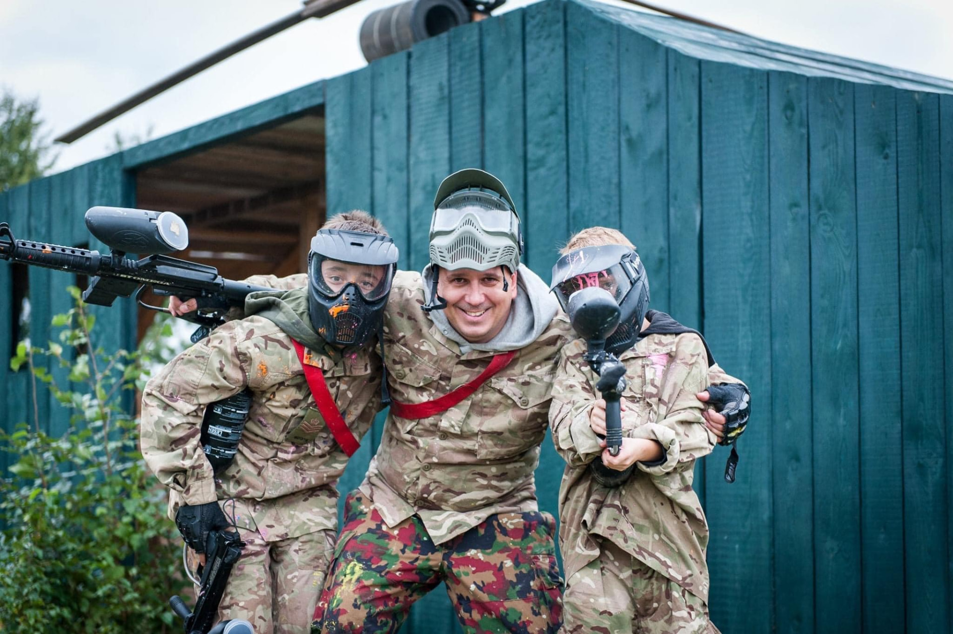 Instruktor z uczestnikami w maskach paintballowych przed chatą